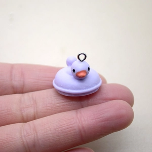 Vue rapprochée d'une breloque canard en résine violette tenue à la main pour l'échelle