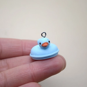 Gros plan d'un petit canard en résine bleu clair sur un doigt pour l'échelle
