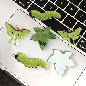 Acryl bedeltjes rups, mot en blad voor DIY-sieraden op een computer toetsenbord