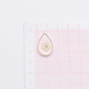 Macro shot of teardrop resin pendant with dried flower and metal frame for DIY jewelry