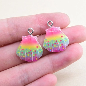 Close-up of rainbow gradient shell resin pendants with glitter dots held in hand