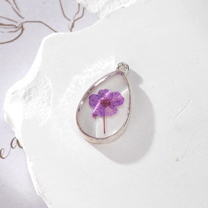 Close-up of teardrop resin pendant with purple dried flower and silver metal bezel