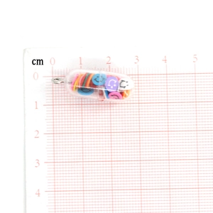 Λεπτομέρεια μενταγιόν κάψουλας smiley 2,3 cm με πολύχρωμες πούλιες σε πλέγμα μέτρησης