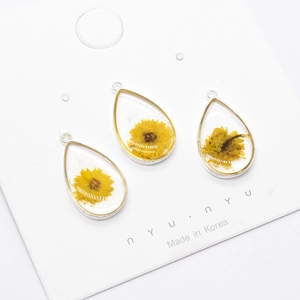 Macro view of teardrop resin charms with yellow dried flowers and silver alloy frames