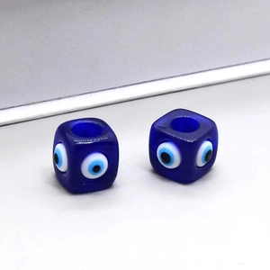 Vue macro de deux perles carrées en résine Evil Eye bleu foncé pour accessoires de bijoux