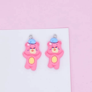Detail of pink resin bear charms with blue hats and silver loops for DIY jewelry making