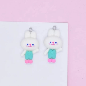 Close-up of cute white resin rabbit charms with mint green overalls for DIY jewelry