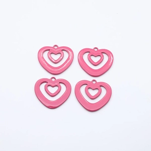 Close-up of four bright pink hollow heart-shaped alloy pendants for jewelry DIY