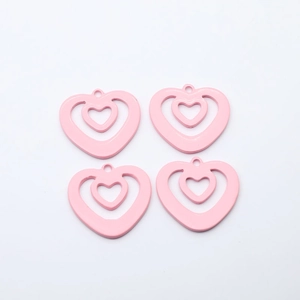 Detail view of four light pink hollow heart-shaped alloy charms for DIY jewelry making