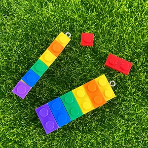Colorful resin brick pendants with silver rings on green grass for DIY jewelry making