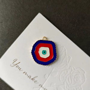 Λεπτομέρεια macro από το μενταγιόν Evil Eye με κυματιστή χρυσή άκρη σε κόκκινο και μπλε