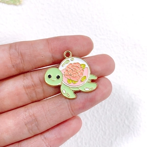 Detailansicht eines Schildkröten-Anhängers aus Emaille mit rosa Blumenmuster und Goldrand