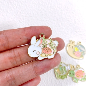 Detail eines weißen Emaille-Kaninchen-Anhängers mit rosa Blumen für DIY-Schmuck