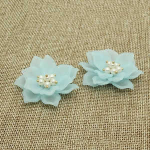 Dettaglio di fiori di camelia azzurri con stami di perle su tessuto di iuta grezza