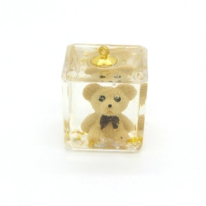 Detail of resin cube charm with teddy bear and gold sequins for DIY jewelry