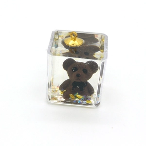 Detailed view of clear resin cube charm with brown bear and colorful glitter flakes