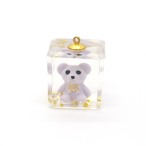 Detailed view of a transparent resin cube pendant with a white bear and gold flakes
