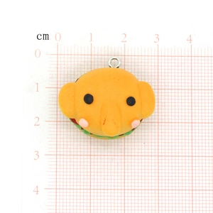 Detailed macro view of a cute cartoon elephant burger resin charm on a grid measurement mat