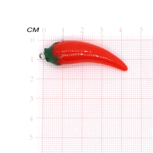 Realistic red chili resin pendant with green stem and silver ring on measurement scale