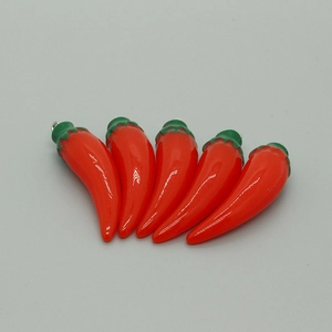 Close-up of five miniature resin chili pepper pendants with metal loops for DIY crafts