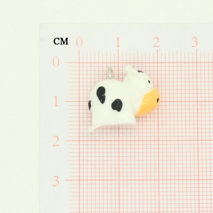 Detailed view of a small cartoon cow charm with dimensions shown on a grid ruler