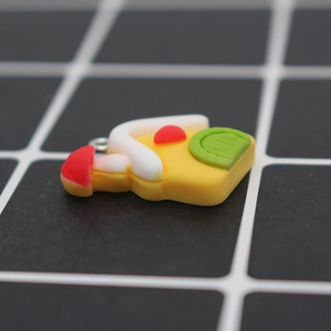 Detail view of a cartoon pizza resin charm with a silver ring on a measuring mat