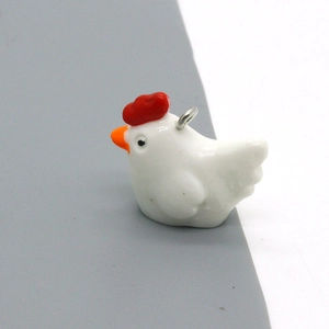 Detailed view of cute ceramic chicken pendant with silver metal ring for DIY jewelry making
