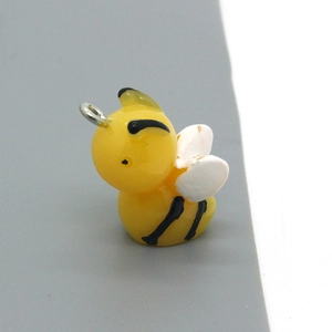 Detail of a cute yellow resin bee pendant with white wings and silver metal ring