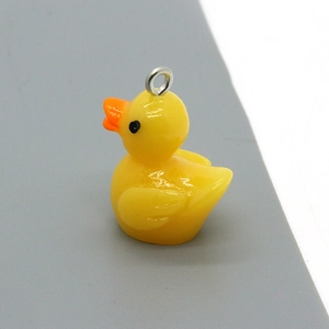 Detailed close-up of a cute yellow cartoon duck charm with a silver metal hanging loop
