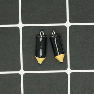 Macro view of two black pencil charms with silver metal rings on a measuring mat