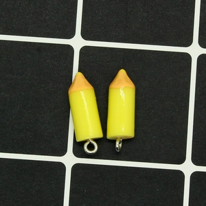 Detailed view of yellow resin pencil pendants with silver loops for DIY craft projects