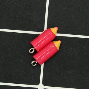 Detail view of two pink resin pencil charms with silver metal eye pins for DIY jewelry