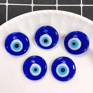 Macro shot of five glass Evil Eye charms for jewelry making on a white ceramic plate