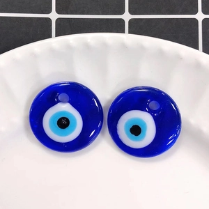 Detail view of two deep blue glass evil eye pendants on a white lace ceramic plate