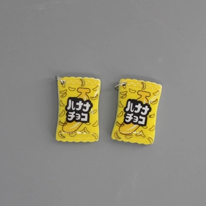 Macro shot of 2 yellow resin banana chocolate snack bag pendants with silver loops