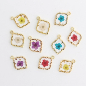 Detail of DIY floral resin pendants with alloy edges and gold leaf foil for jewelry