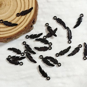 Macro detail of glossy black feather pendants for DIY jewelry making on wooden prop