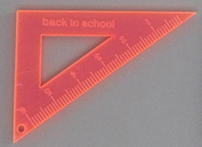 Macro detail of orange acrylic triangle ruler pendant with 6cm scale for DIY jewelry