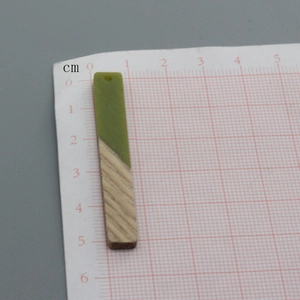 Groene hars en houten rechthoekige hanger voor DIY-sieraden op een meetraster getoond