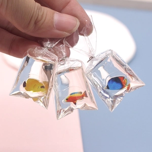 Handheld view of creative simulated goldfish bag charms in yellow, orange, and blue colors
