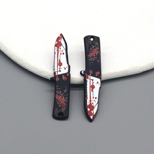 Macro shot of two bloody dagger charms for Halloween jewelry DIY crafts with red splatter