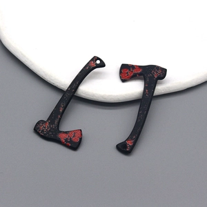 Macro detail of blood-splattered black axe charms for Halloween jewelry making