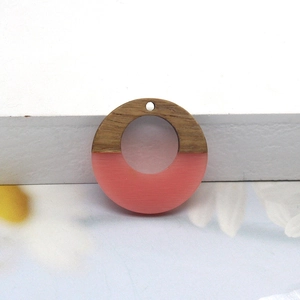 Macro detail of round geometric pendant crafted from wood and pink translucent resin