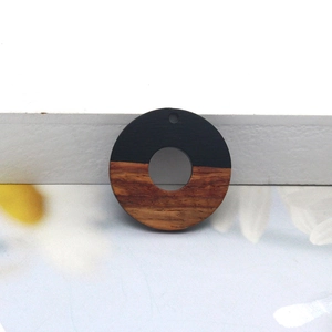 Detail of round wood and black resin pendant with gold foil and natural grain texture
