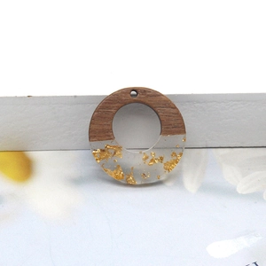 Close-up of a circular resin and wood pendant with gold foil flakes for DIY jewelry