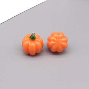Dettaglio di ciondoli a zucca in resina per Halloween con piccioli verdi e anelli metallici