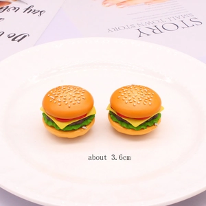 Detailed macro view of 3.6cm realistic miniature PVC burger charms on a white ceramic plate