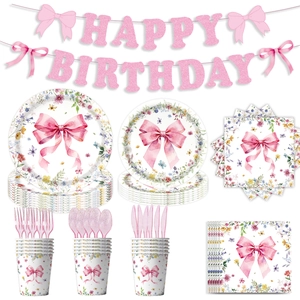 Close-up of pink bow and wildflower party tableware set with glittery birthday banner