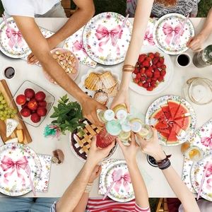Flat lay of floral bow disposable plates and napkins on a festive wooden table set