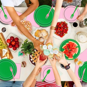 Détail d'assiettes en carton rose et vert à pois dorés avec couverts assortis